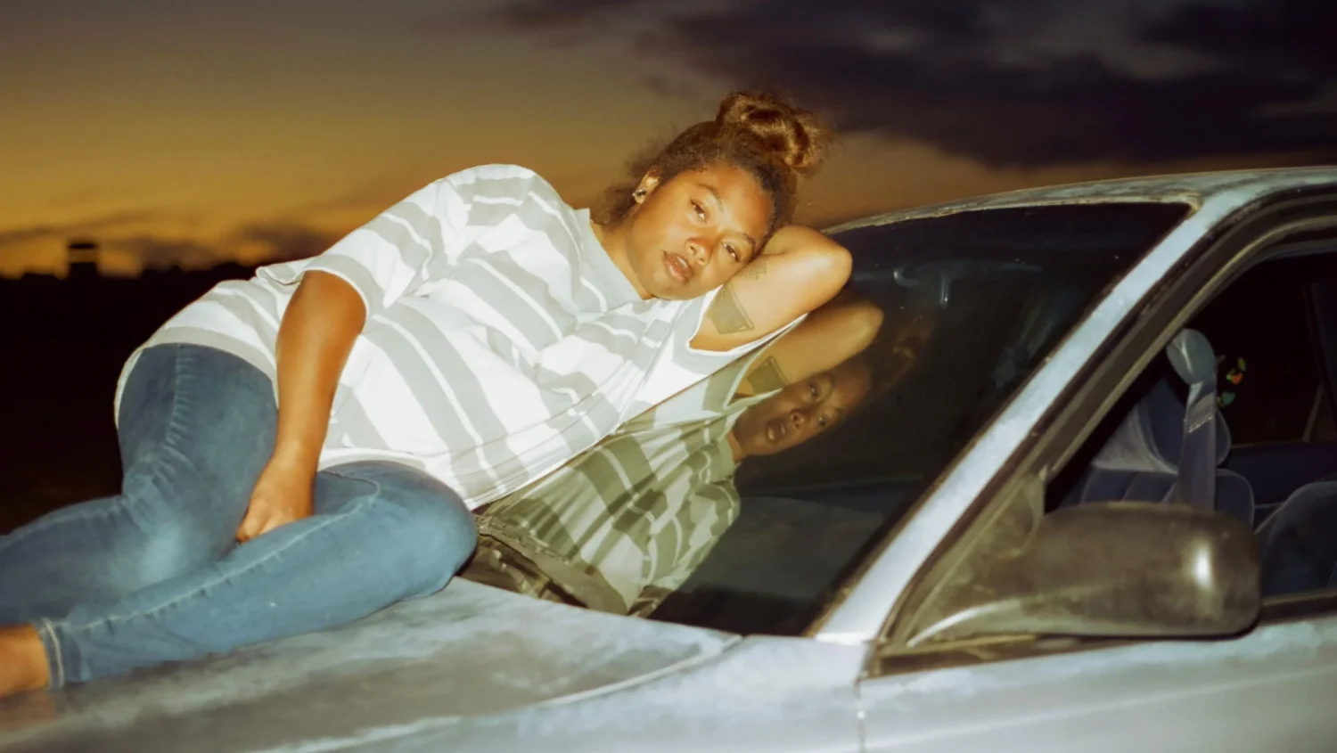 Bilde fra filmen Earth Mama - kvinne liggende på et bilpanser
